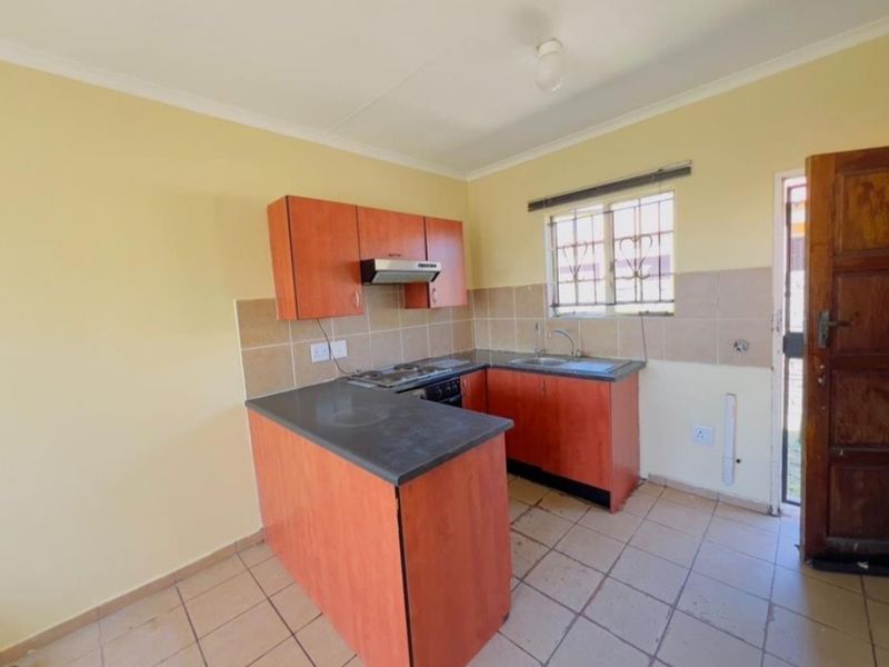 A functional kitchen featuring built-in cabinetry, laminate countertops, a stainless steel sink, and tiled flooring, offering a clean and practical workspace.