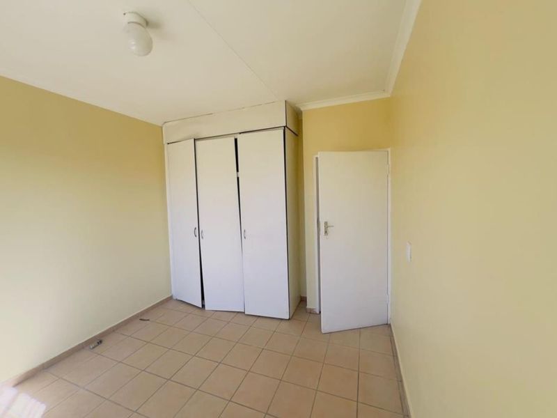 An empty bedroom featuring tiled flooring and built-in cupboards, offering a blank canvas for personalization and renovation.