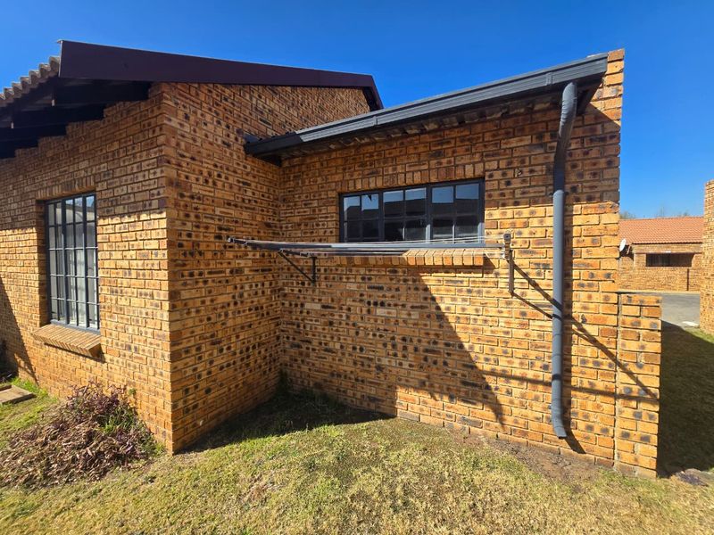 Exterior view of the townhouse rear facade featuring face brick construction, steel-framed windows, and a functional wall-mounted fold-down washing line.
