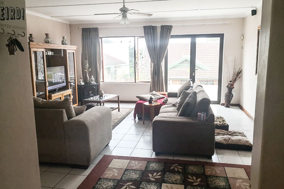 A spacious living room featuring tiled flooring, a ceiling fan, and large sliding glass doors that provide natural light and access to the exterior.