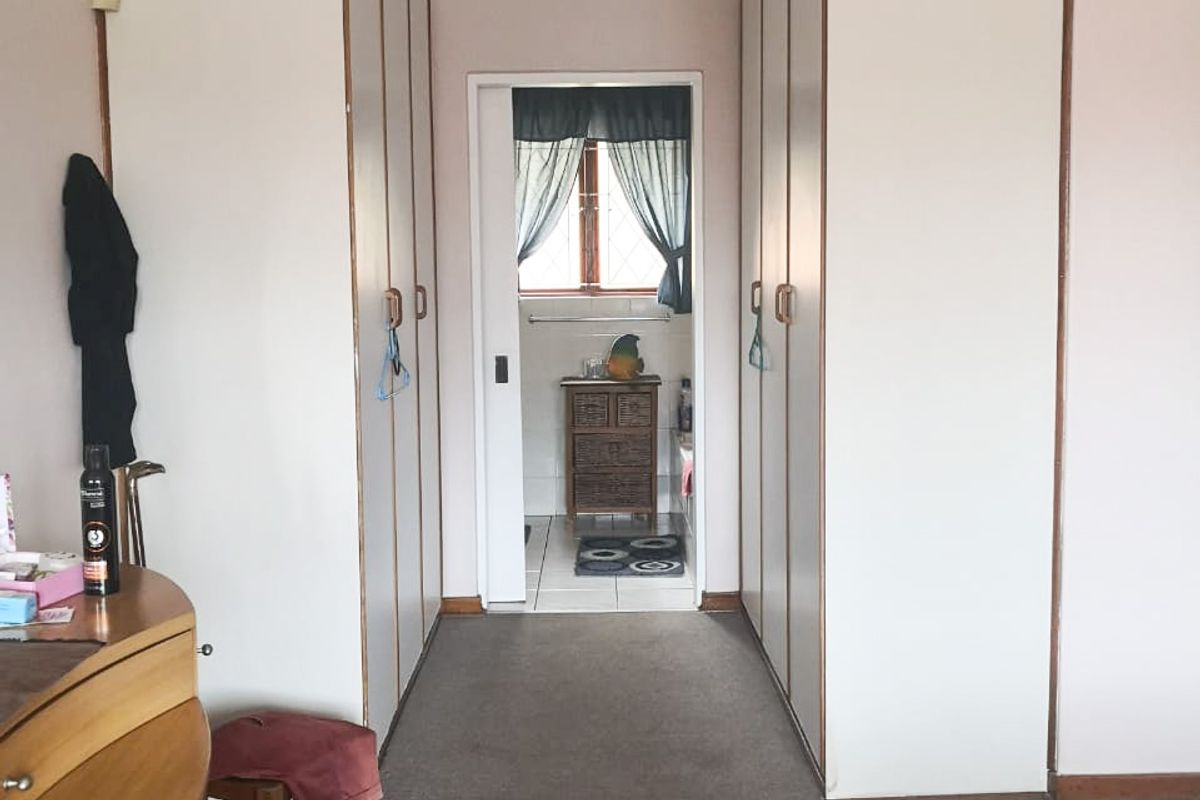 Bedroom featuring extensive built-in cupboard storage and carpeted flooring, with a direct view through a sliding door into the adjoining bathroom.