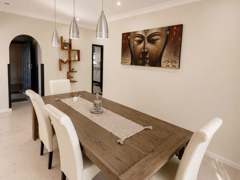 A well-maintained dining room featuring modern pendant lighting, laminate flooring, and an elegant archway leading to adjacent living spaces.