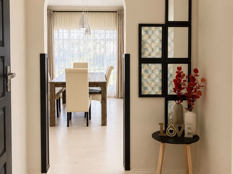 A bright, welcoming hallway featuring an elegant arched doorway leading into a dining area with light wood-look flooring and modern recessed lighting.