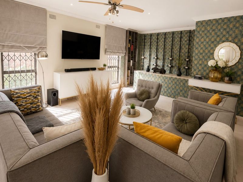 A well-appointed living room featuring recessed lighting, a ceiling fan, and custom built-in shelving with decorative wallpaper accents.