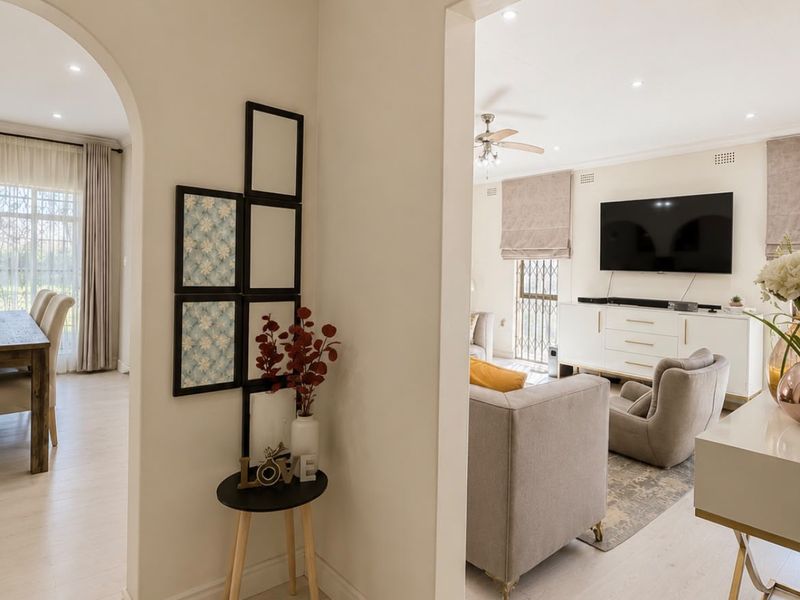 A bright, well-maintained hallway featuring an elegant archway leading into the living and dining areas, with modern laminate flooring and recessed lighting.