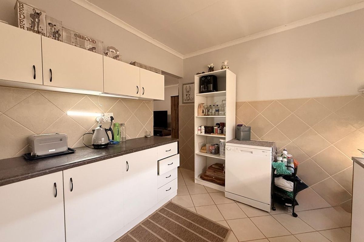 A functional kitchen featuring white cabinetry, laminate countertops, tiled backsplash, and tiled flooring, offering a clean and practical workspace.