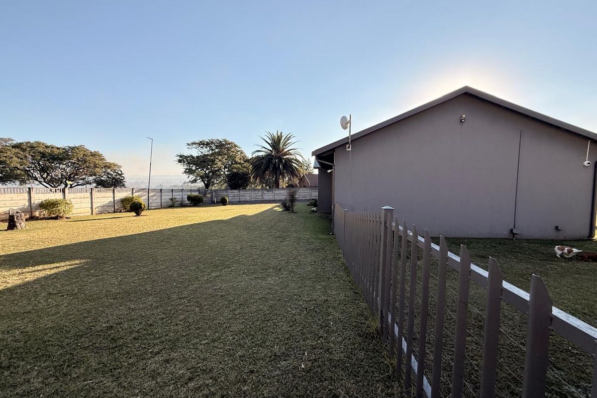 Spacious rear garden featuring a well-maintained lawn, enclosed by a precast concrete boundary wall and a metal picket fence.