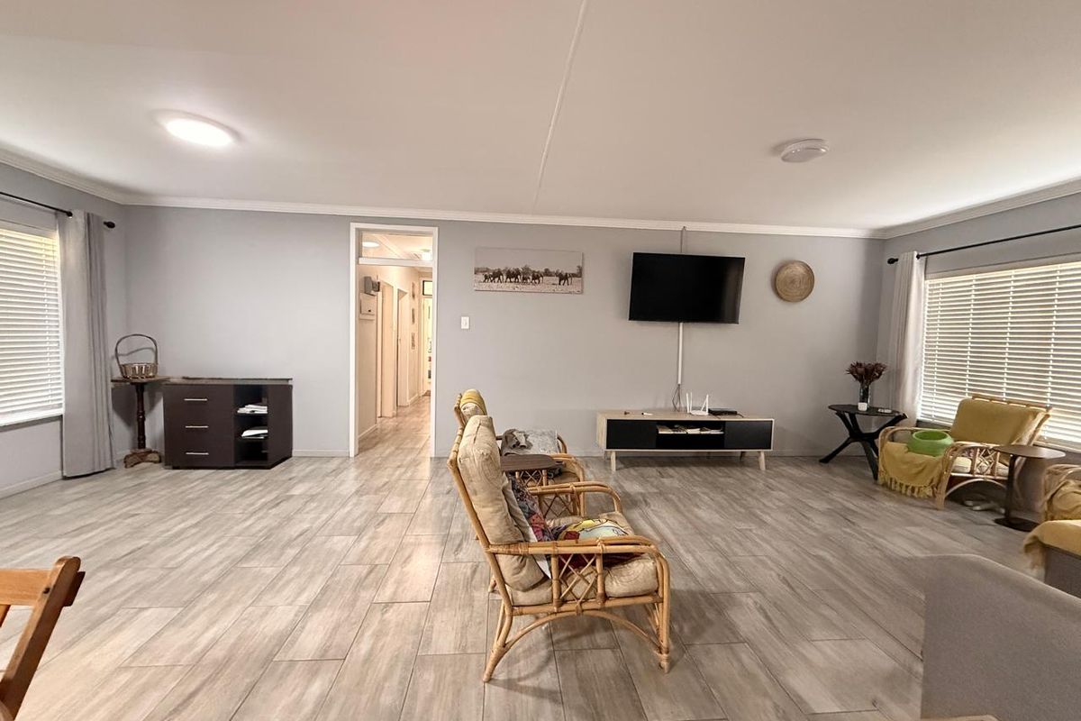 Spacious living room featuring neutral grey walls, modern wood-look tiled flooring, and ample natural light through dual windows.