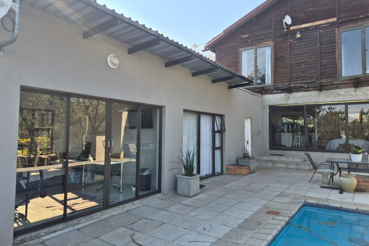 Rear exterior view featuring a paved patio area, swimming pool, and a combination of rendered walls and timber-clad upper level architecture.