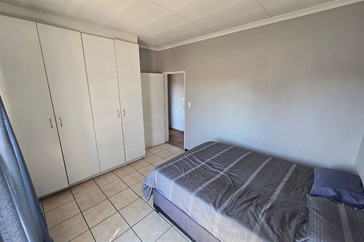 A functional bedroom featuring tiled flooring and built-in cupboards, offering a neutral space ready for personalization.