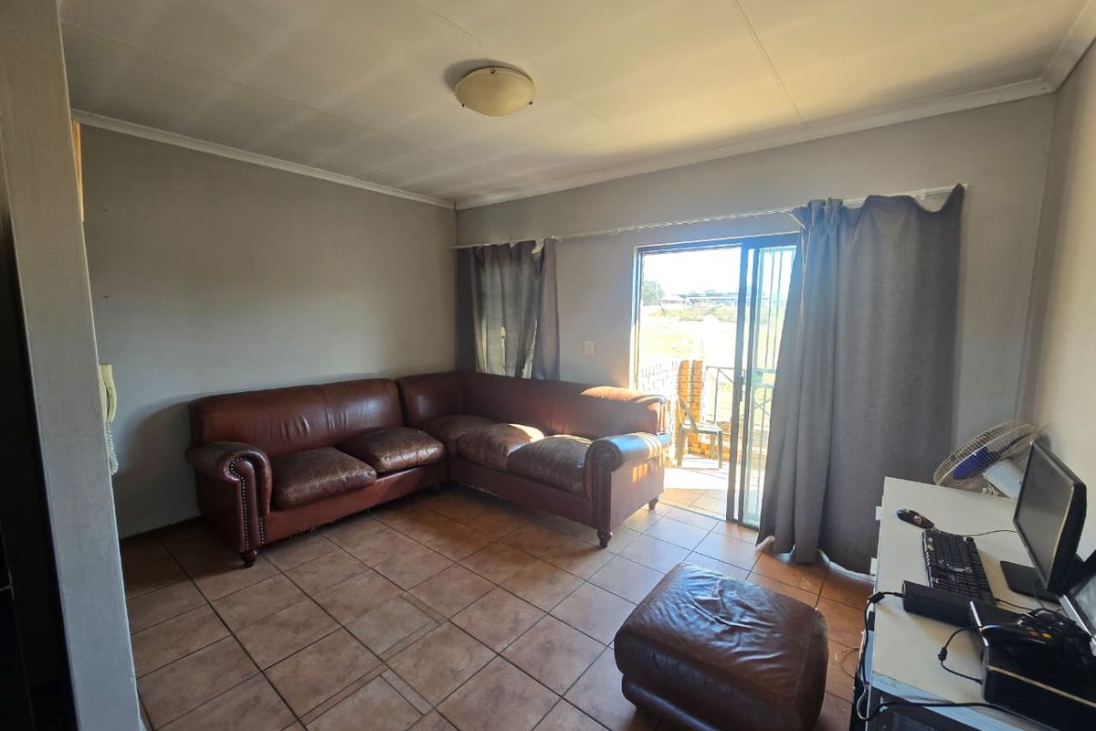 A living room featuring tiled flooring and a sliding glass door providing access to an outdoor area.