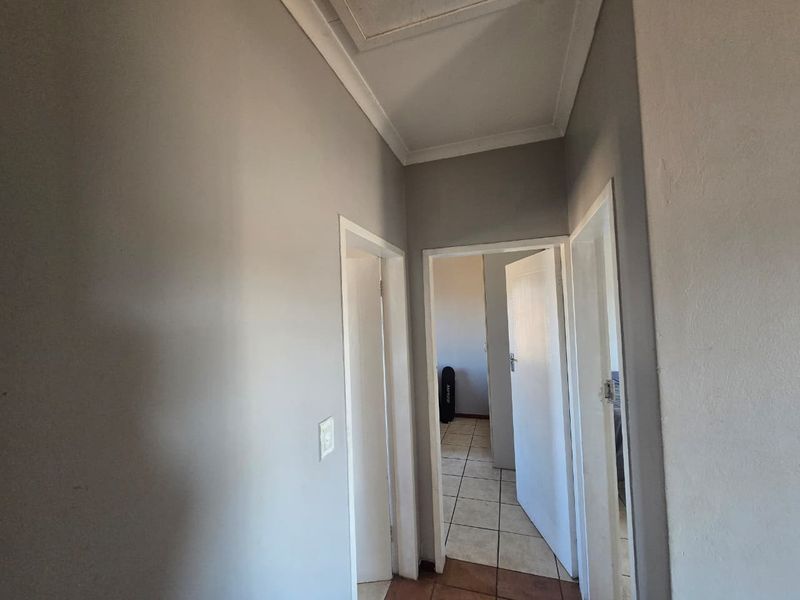 A functional hallway featuring tiled flooring, neutral wall paint, and access to multiple rooms, providing a clean transition space within the townhouse.