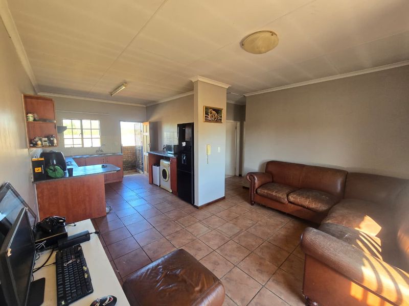 Open-plan living area featuring tiled flooring and an integrated kitchen space with cabinetry, providing a functional layout for daily living.