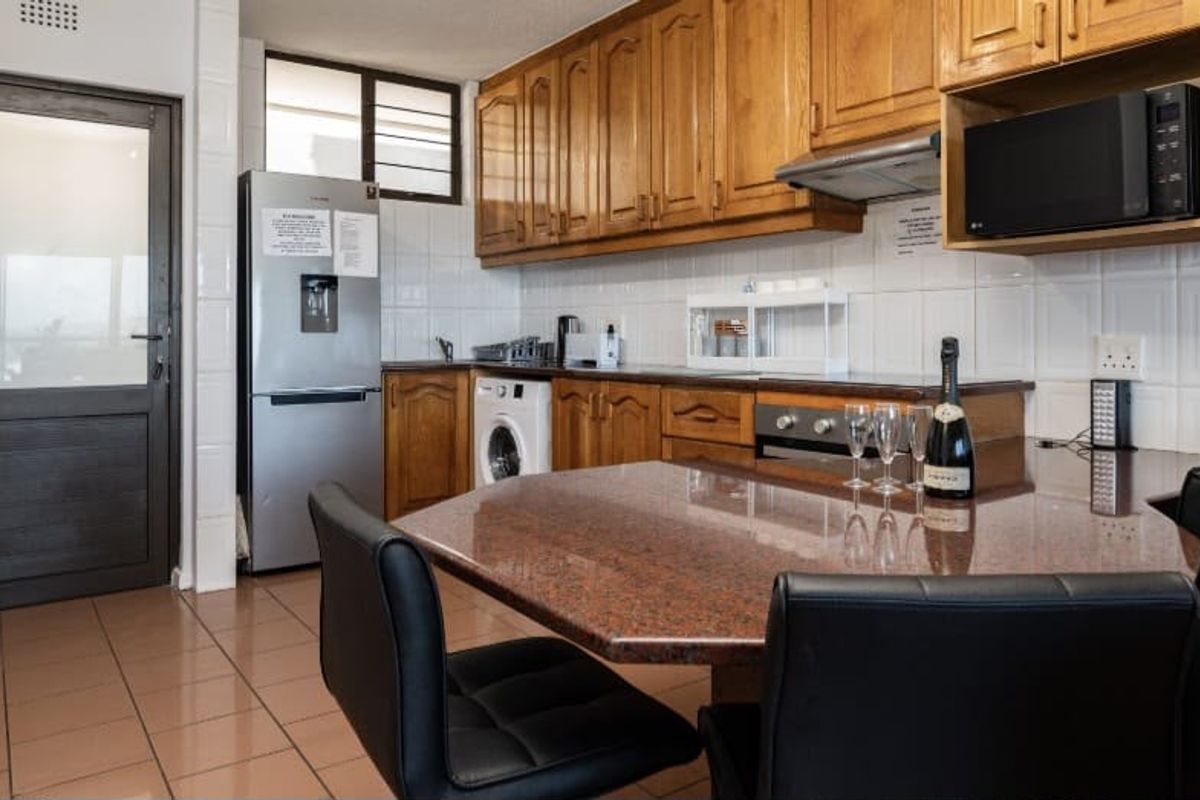 A functional kitchen featuring wooden cabinetry, granite countertops, a built-in oven, and tiled finishes, providing a practical space for cooking and dining.