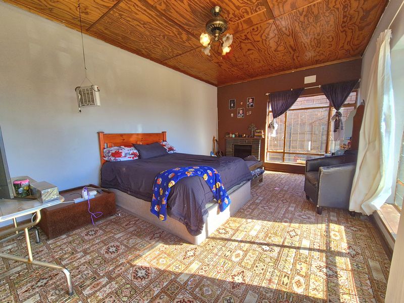 Spacious bedroom featuring a wood-paneled ceiling, a built-in fireplace, and large windows that provide ample natural light.