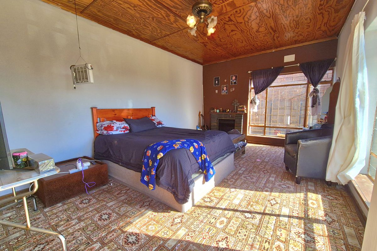 Spacious bedroom featuring a wood-paneled ceiling, a built-in fireplace, and large windows that provide ample natural light.