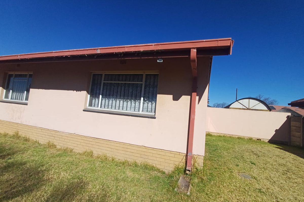 Rear exterior view of the property featuring plastered walls, brick plinth, and metal guttering system.