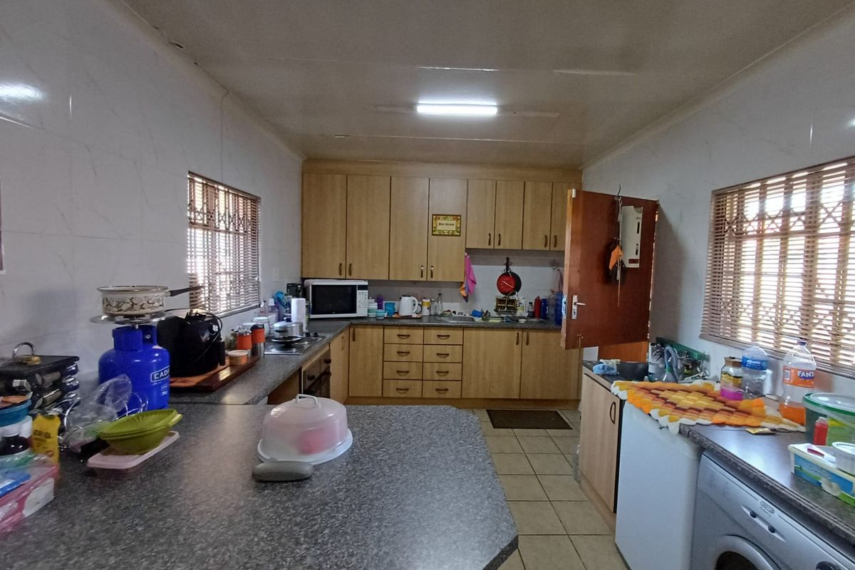Functional kitchen featuring laminate cabinetry, tiled walls, and ample counter space, offering a practical layout for daily meal preparation.
