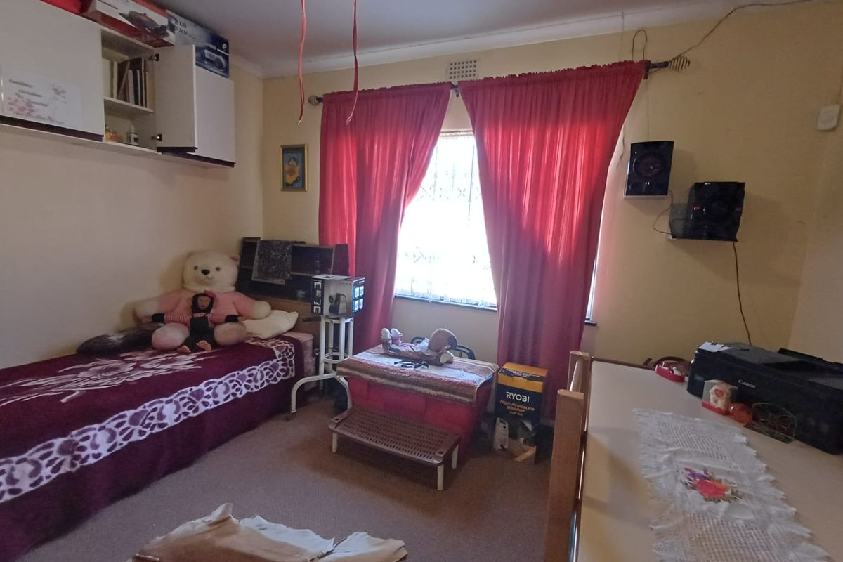 A bedroom featuring built-in wall cabinetry, security bars on the window, and coving, requiring cosmetic updates to improve the overall finish.