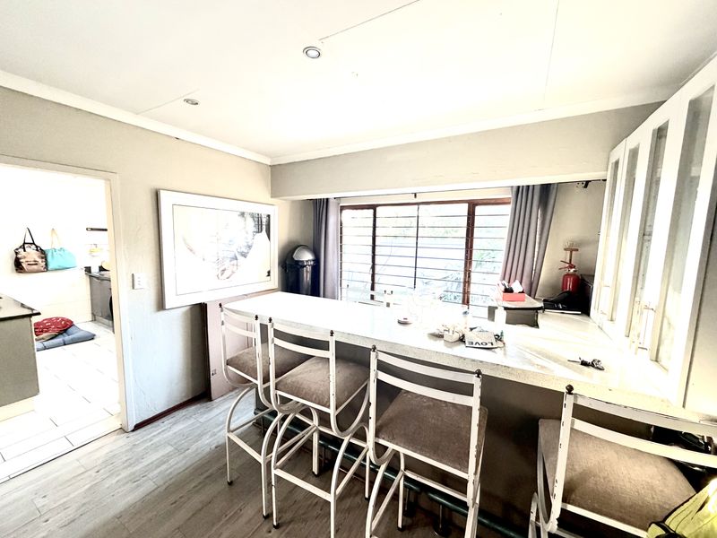 A kitchen area featuring a breakfast bar with stone countertops, built-in cabinetry, and recessed lighting, with an adjacent view into a secondary utility space.