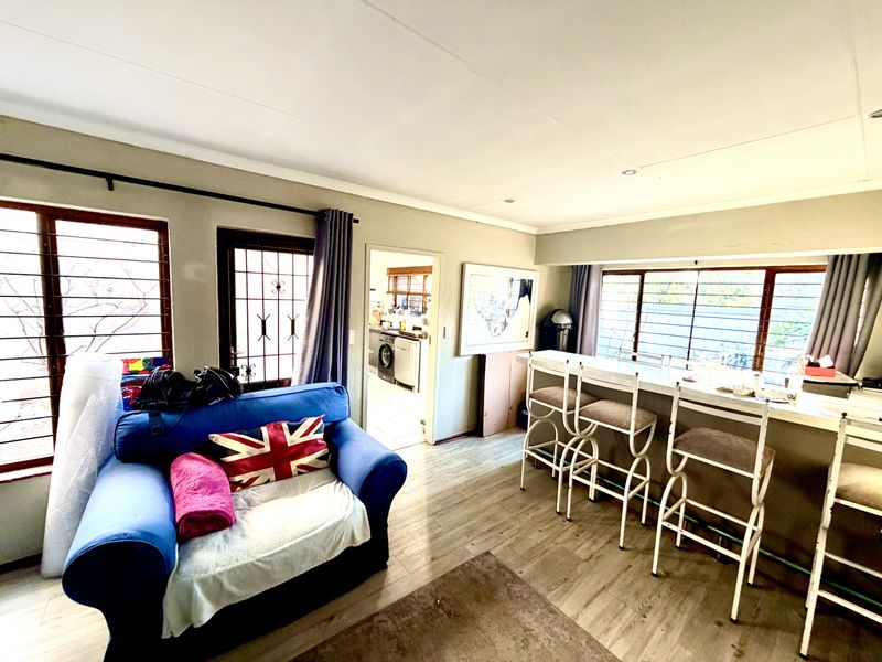 Open plan living area featuring laminate flooring, a built-in breakfast bar, and direct access to the kitchen and outdoor area.