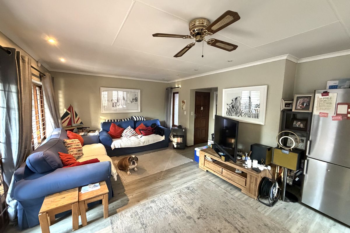 A comfortable living room featuring laminate flooring, a ceiling fan, and recessed lighting, providing a functional and inviting space for relaxation.