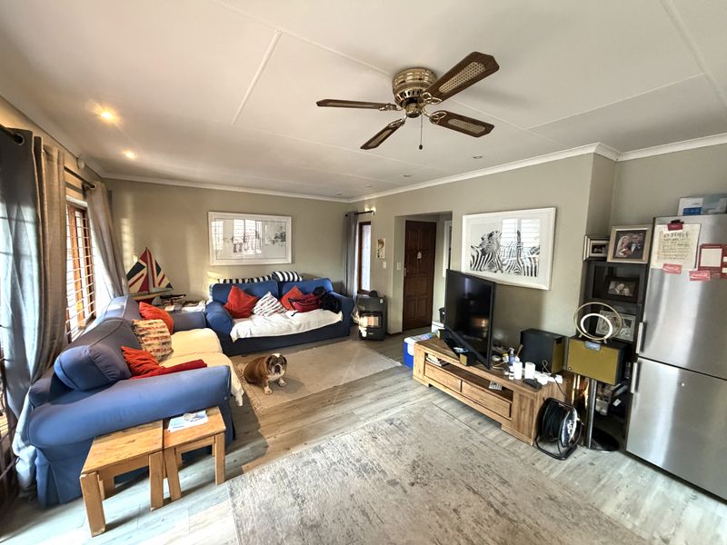 A comfortable living room featuring laminate flooring, a ceiling fan, and recessed lighting, providing a functional and inviting space for relaxation.