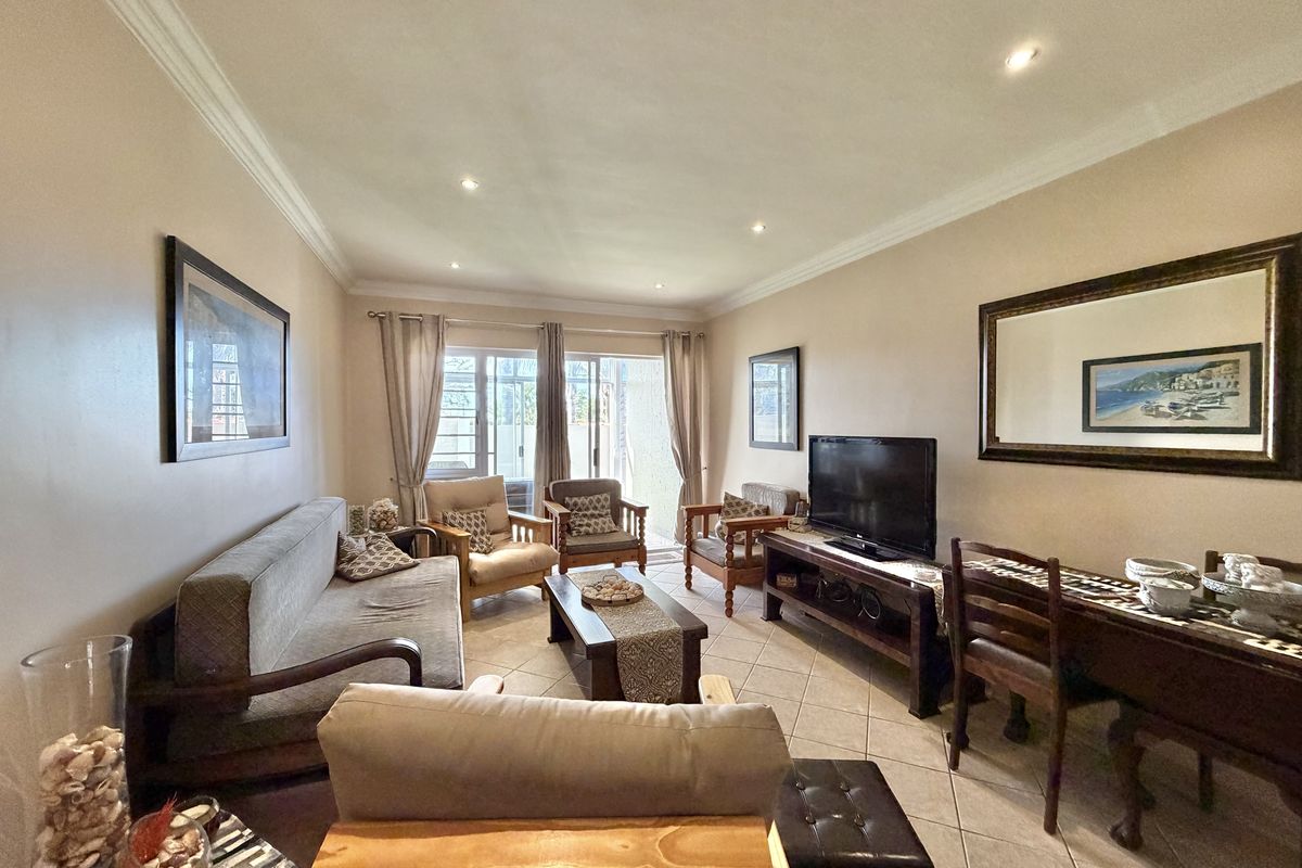A comfortable living room featuring tiled flooring, recessed lighting, and a sliding glass door providing access to the outdoor area.