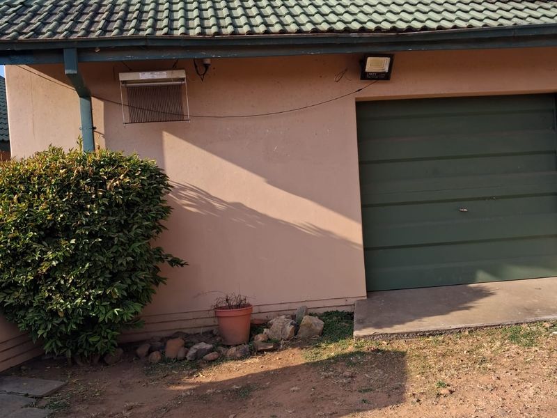 Exterior view of a single garage featuring a green tiled roof, matching garage door, and external security lighting.