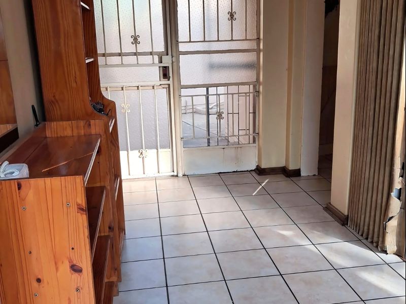 Entrance area featuring tiled flooring and a security gate, with a folding door leading to adjacent living spaces.