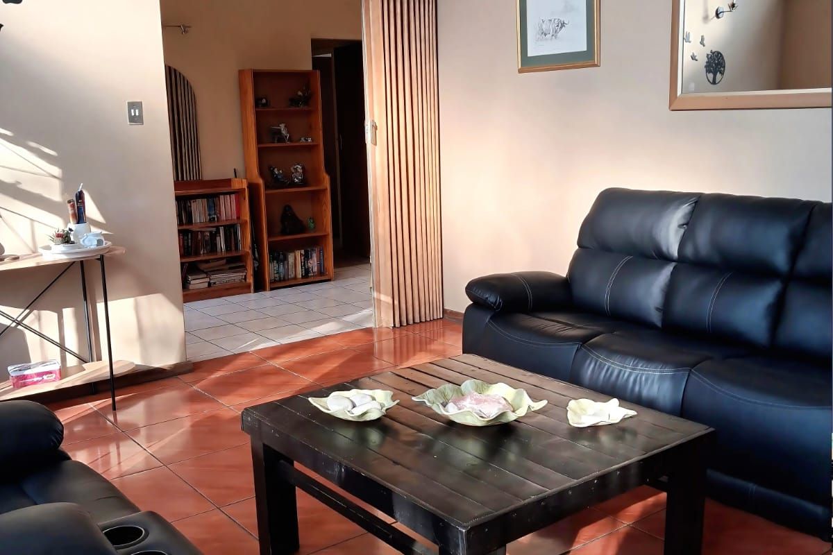 A living room featuring ceramic floor tiles, a folding room divider, and wall-mounted lighting fixtures.