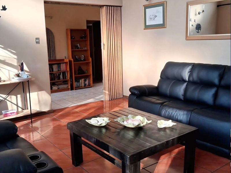 A living room featuring ceramic floor tiles, a folding room divider, and wall-mounted lighting fixtures.