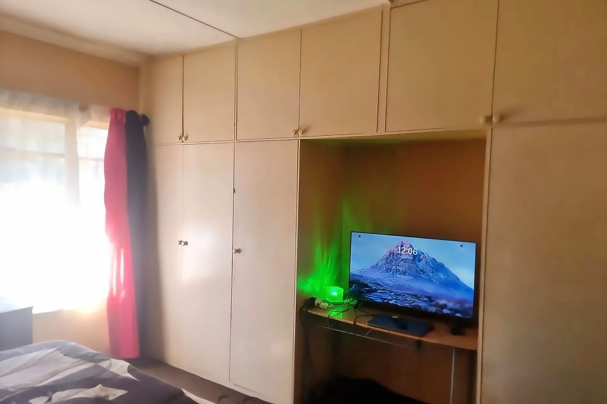 A bedroom featuring extensive floor-to-ceiling built-in cupboards with integrated overhead storage and a central recessed alcove.