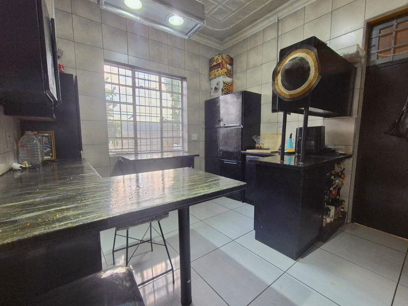 A functional kitchen featuring tiled walls and flooring, built-in cabinetry, and laminate countertops, offering a practical layout with natural light from the window.