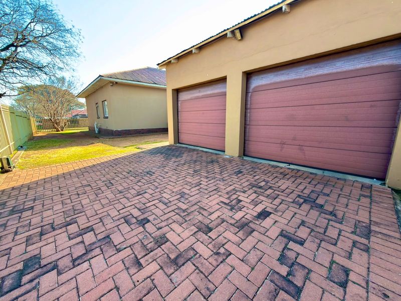 Exterior view of a double garage with a paved driveway and adjacent garden area.
