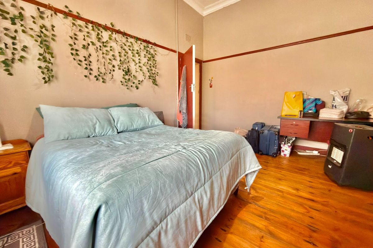 Spacious bedroom featuring original timber flooring, ornate ceiling detailing, and classic picture rails, offering a character-filled foundation for renovation.