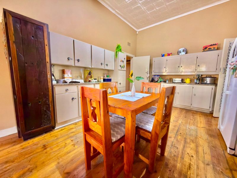 A kitchen featuring timber flooring, pressed metal ceilings, and ample built-in cabinetry with laminate countertops, offering a functional and character-filled space.