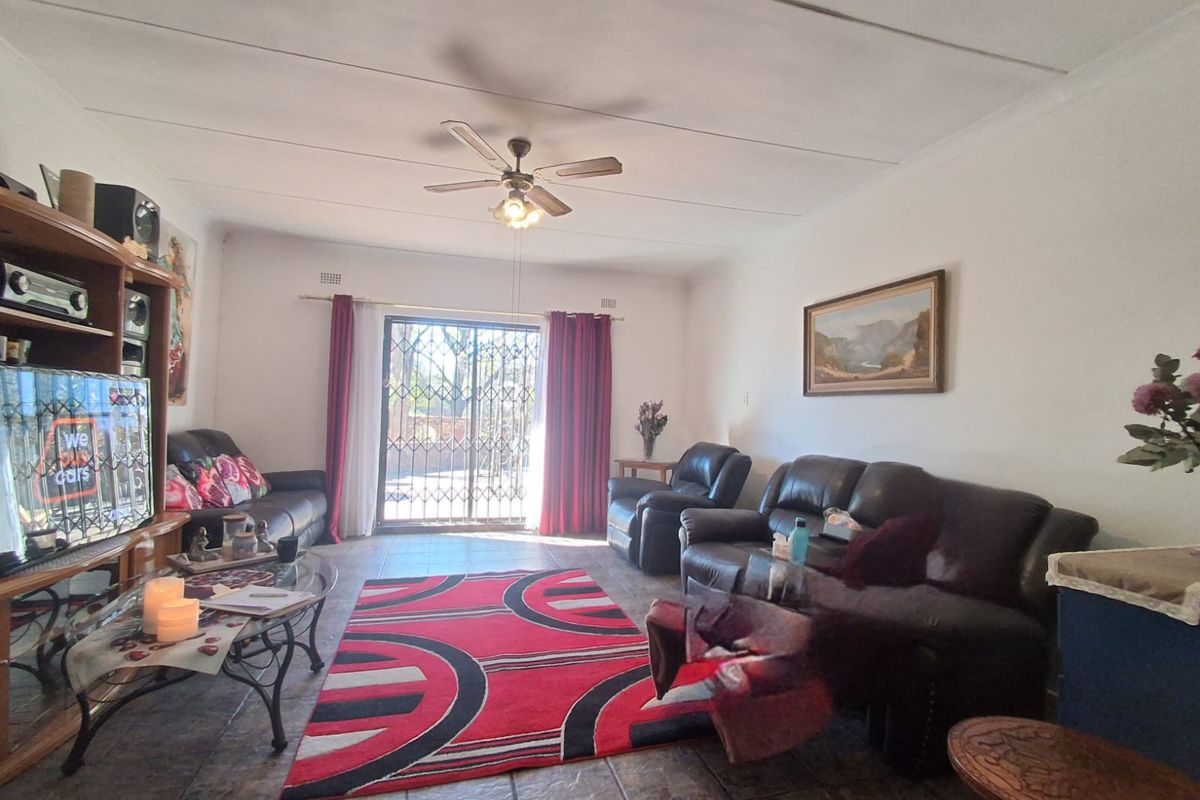 Spacious living room featuring tiled flooring, a ceiling fan, and a sliding glass door with a security gate leading to the exterior.