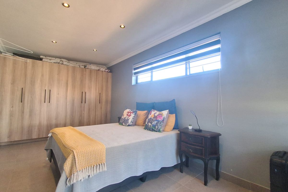 A well-maintained bedroom featuring neutral tiled flooring, recessed downlighting, and extensive built-in wooden cabinetry for storage.