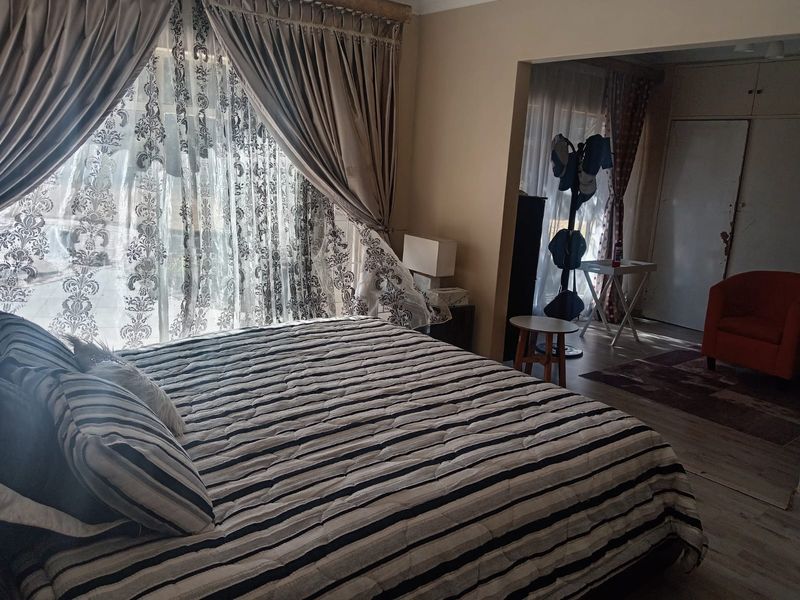 Spacious bedroom featuring laminate flooring and a built-in cupboard, with direct access to an adjoining area.