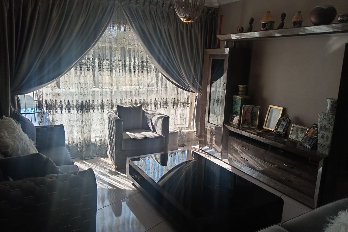 A well-maintained living room featuring tiled flooring, built-in cabinetry, and large windows with elegant drapery, creating a comfortable and inviting atmosphere.
