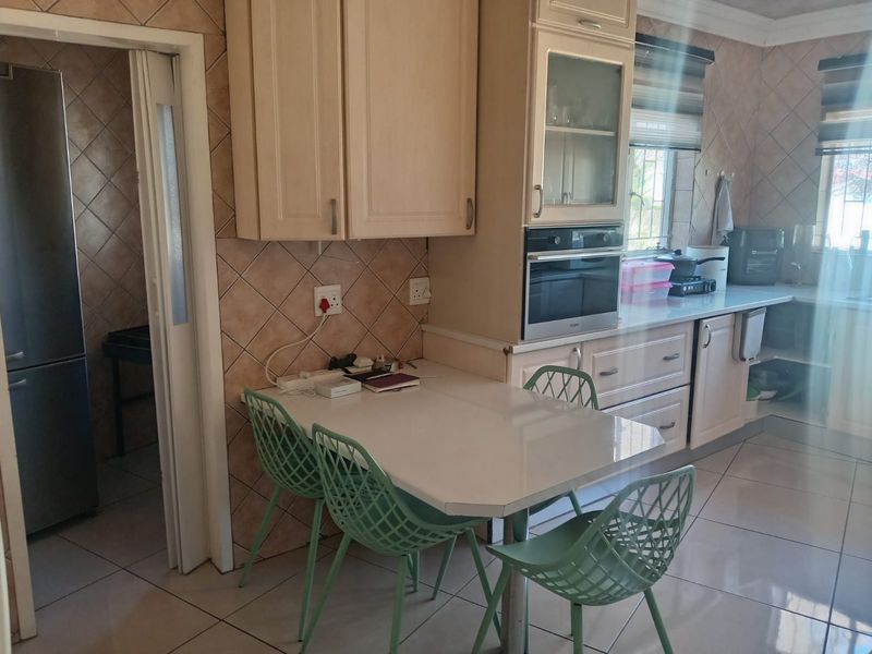 A functional kitchen featuring built-in cabinetry, a wall-mounted oven, tiled backsplash, and tiled flooring, with an adjacent doorway leading to a utility area.