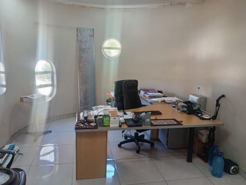 A circular office space featuring unique porthole windows and tiled flooring, offering a distinct architectural layout suitable for a home workspace.