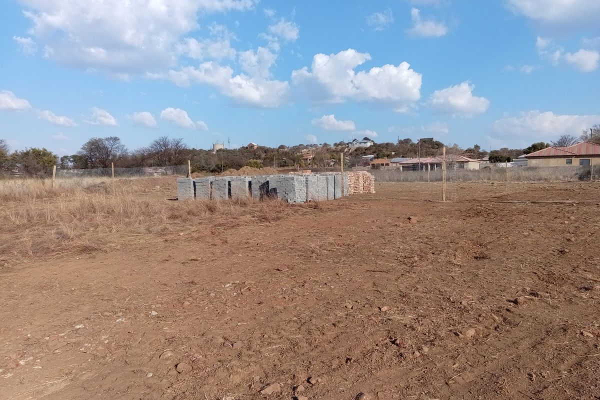 A vacant residential plot featuring cleared earth, wire perimeter fencing, and a stack of construction materials ready for development.