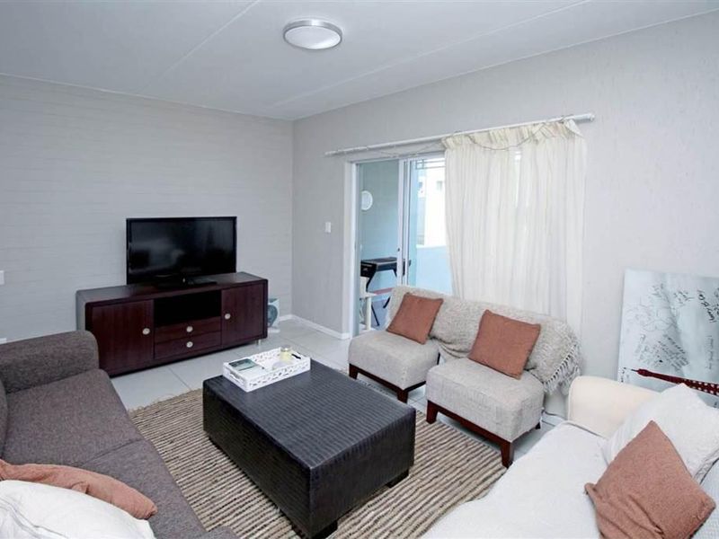 A comfortable living room featuring tiled flooring and a sliding glass door providing access to an outdoor area.
