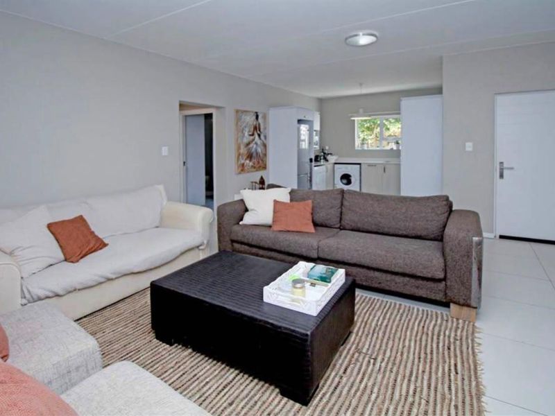 Open-plan living area featuring tiled flooring and a connected kitchen space with built-in cabinetry and laundry appliance connections.