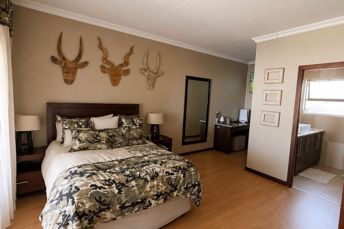 Spacious bedroom featuring laminate flooring, neutral wall tones, and an adjoining en-suite bathroom with a built-in vanity.