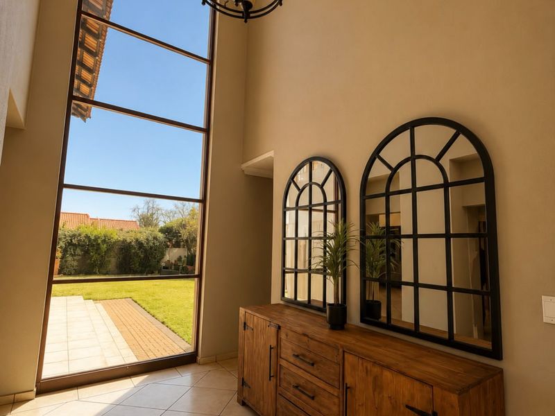 Spacious double-volume entrance hall featuring large floor-to-ceiling windows that provide abundant natural light and a view of the rear garden.