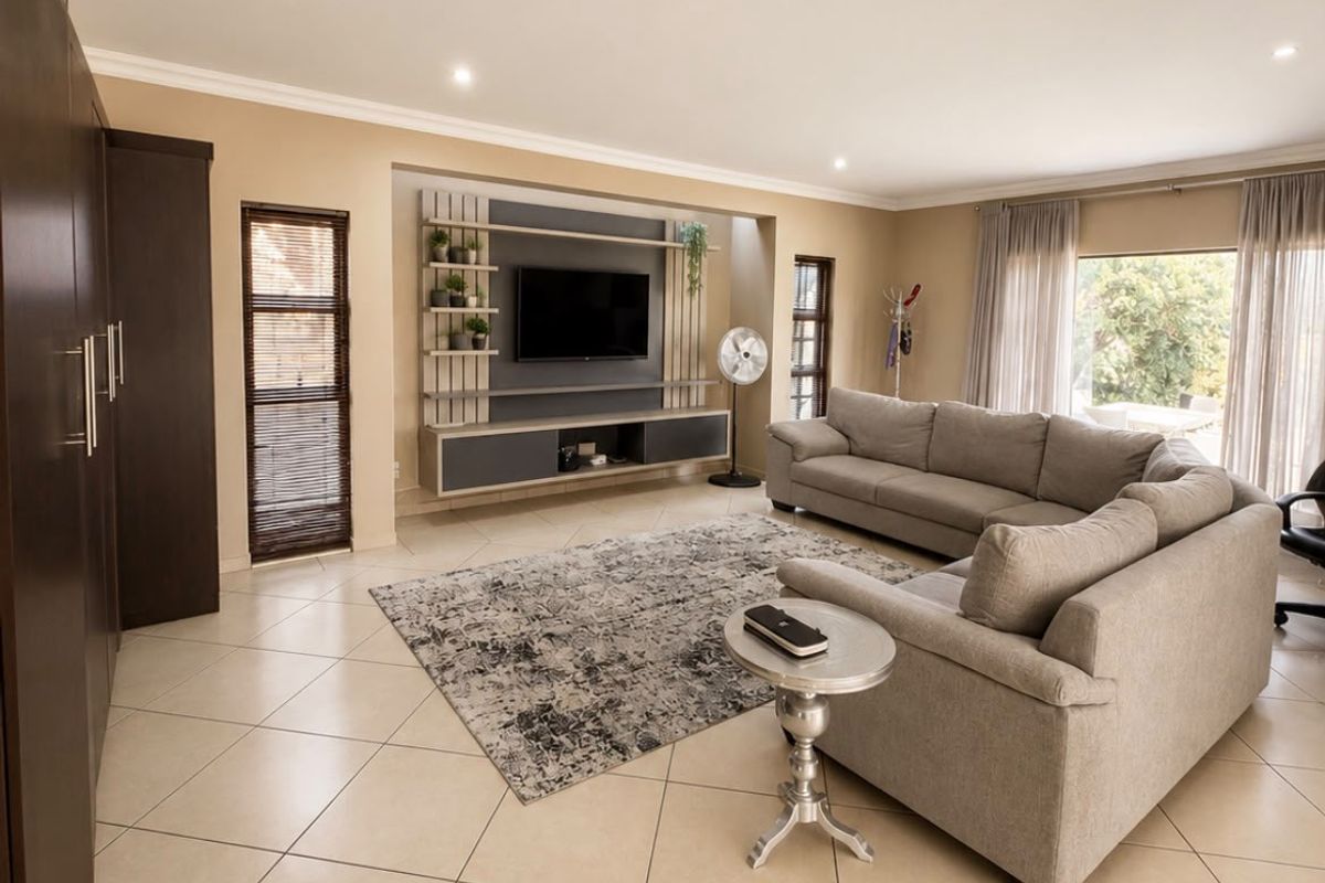 Spacious living room featuring tiled flooring, recessed lighting, and a custom built-in media unit with integrated shelving.