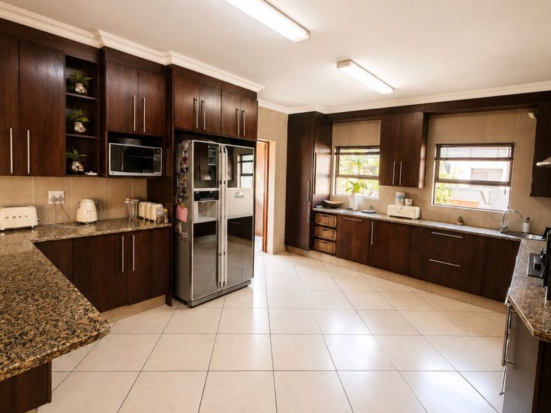 Spacious kitchen featuring dark wood cabinetry, granite countertops, and tiled flooring, offering ample storage and workspace.